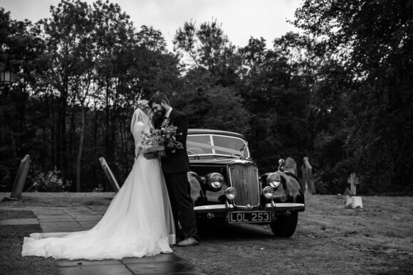 Bride and Groom at church wedding with vintage car black and white photograph